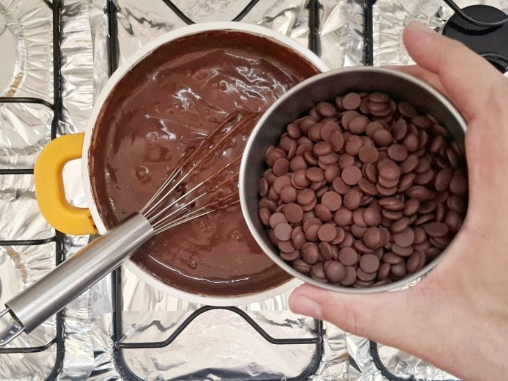 Chocolate meio amargo sendo adicionado a panela.