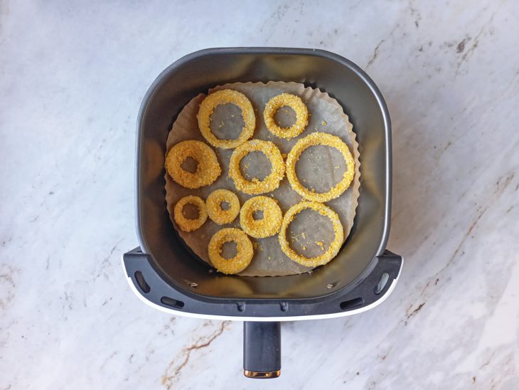 Anéis de cebola dispostos na air fryer.
