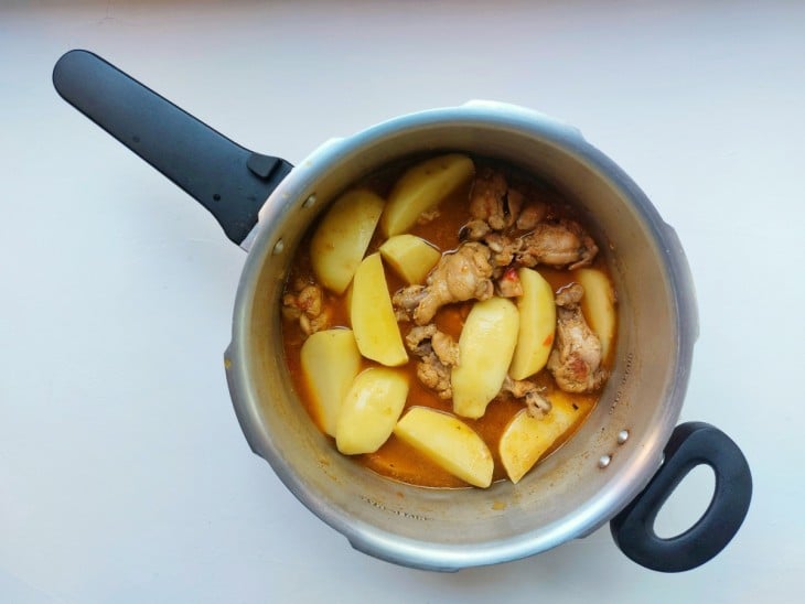 Frangos cozidos com batatas cruas por cima.