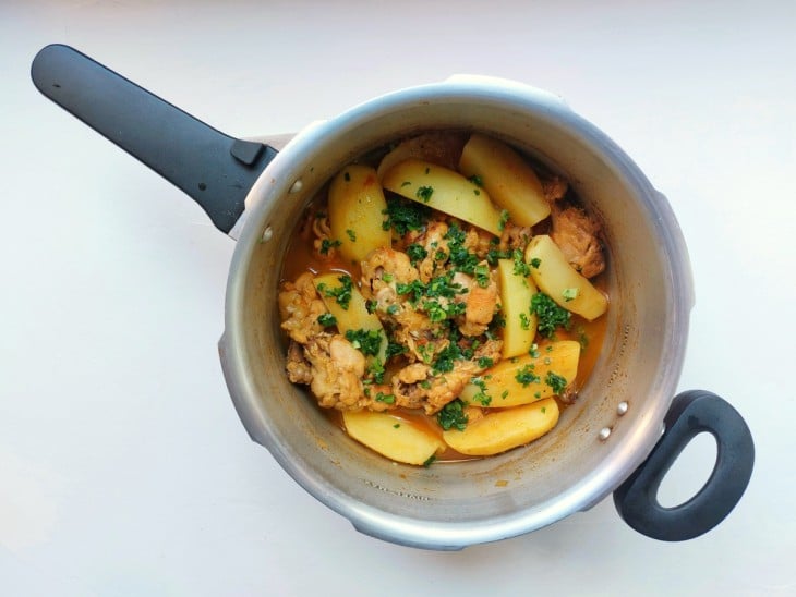 Frangos e batatas cozidos com cheiro-verde por cima.