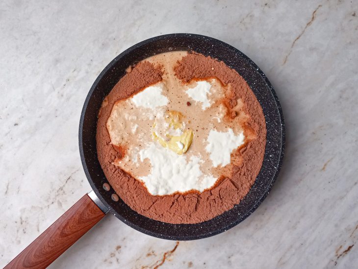 Numa panela, o creme de leite, o leite, o leite condensado, o cacau e a manteiga.