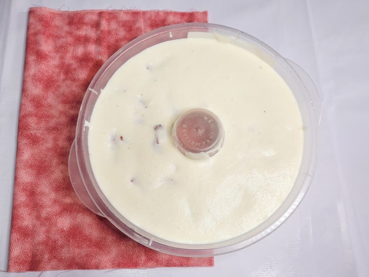Uma forma contendo creme branco e pedacinhos de morango.