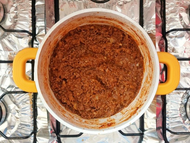 Uma panela com carne moída temperada e passata de tomate ao fogo.