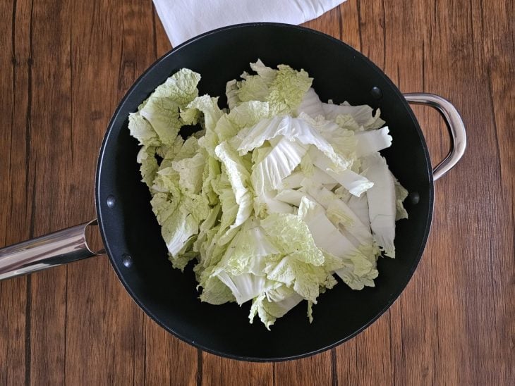 Uma frigideira com óleo e a acelga fatiada.