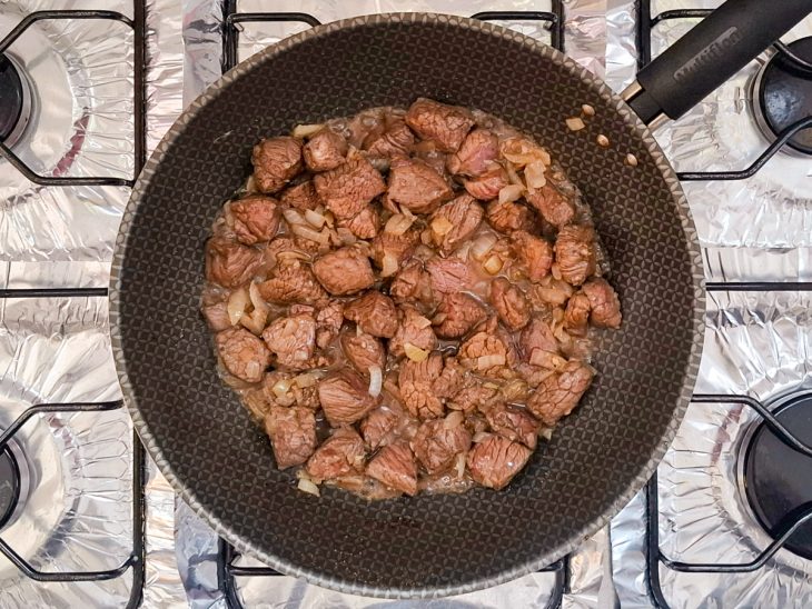 carne temperada refogando junto ao alho e cebola dourados.
