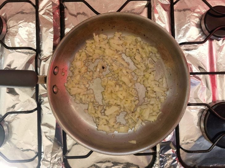 Uma panela com azeite, alho e cebola.