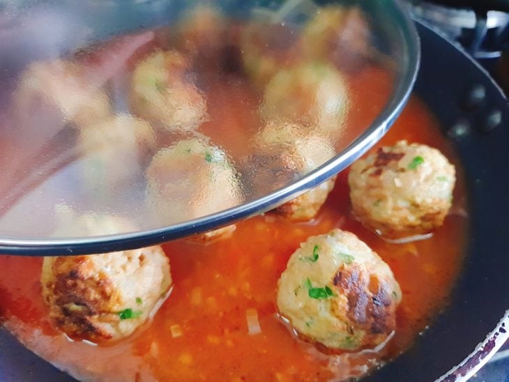 Frigideira com ingredientes do molho e almôndegas misturados.