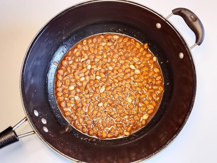 Uma frigideira com amendoins, açúcar, água, fermento e chocolate em pó.