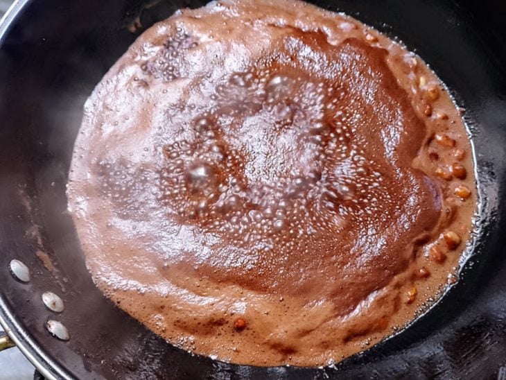 Uma frigideira com os amendoins e caldo fervendo.