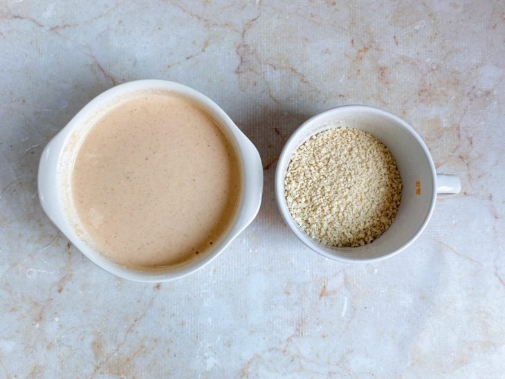 Farinha panko e mistura para empanar os anéis de cebola em recipientes distintos.