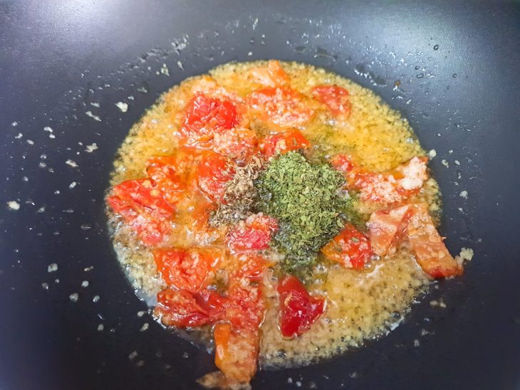 Uma panela com azeite, cebola, alho, pimenta-dedo-de-moça, tomate, salsinha e orégano.