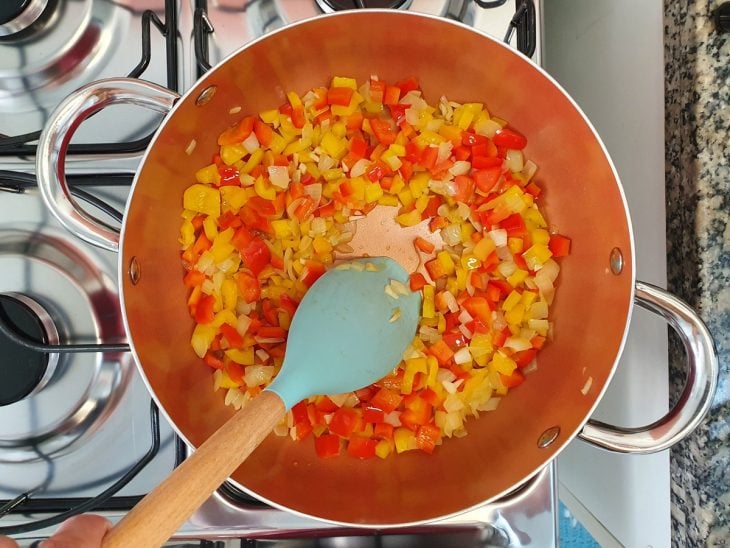 Panela com pimentões e outros ingredientes refogados.