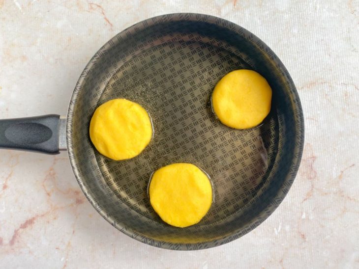 Arepas fritando na frigideira com óleo.