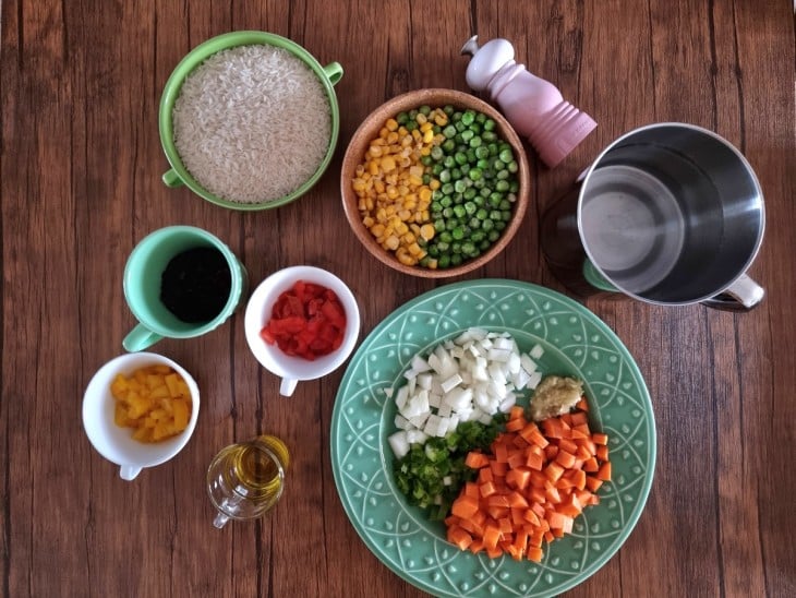 Todos os ingredientes do arroz à grega tradicional reunidos na bancada.