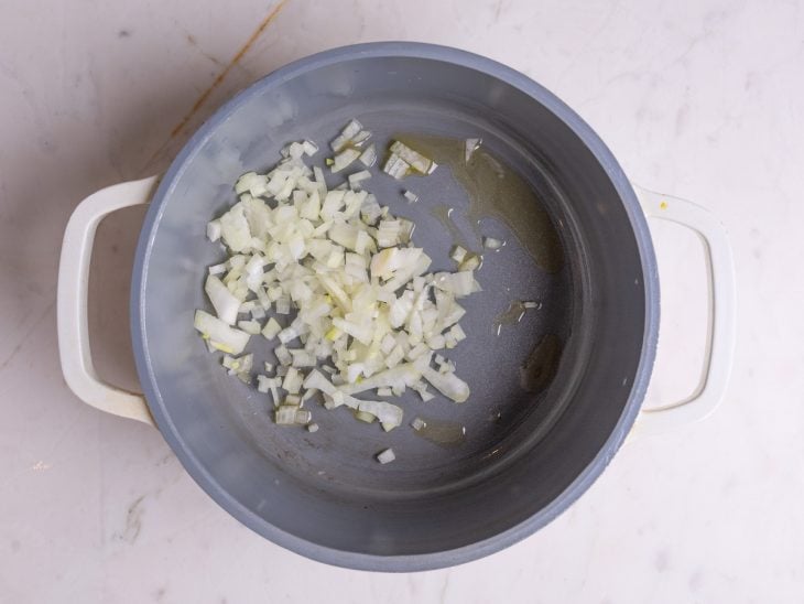 Uma panela com azeite e cebola a dourar.