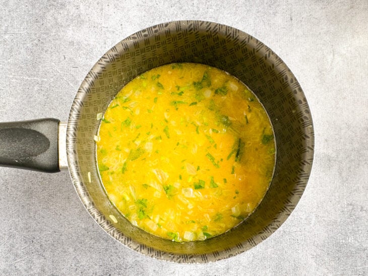 Água quente, açafrão, sal e salsinha sendo adicionados e misturados ao arroz.