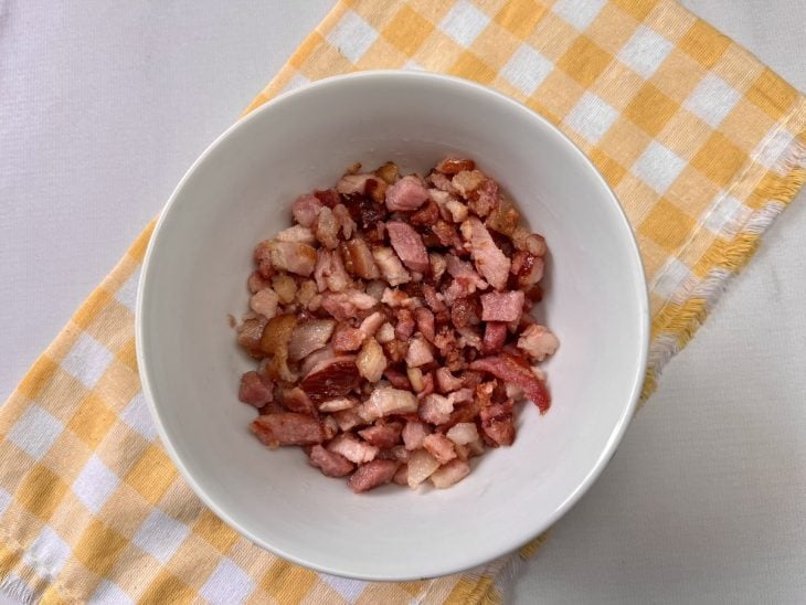 Recipiente com bacon em cubos fritos.