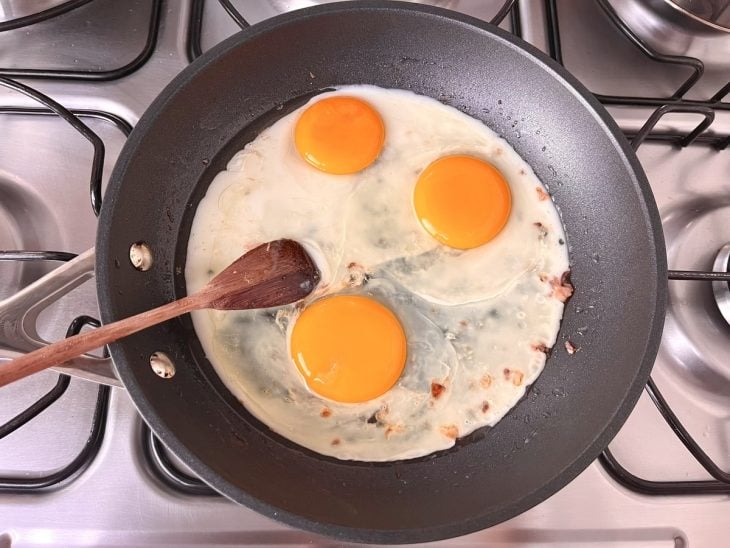 Frigideira com 3 ovos fritando.