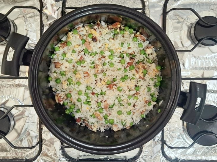 Arroz cozido e ervilhas adicionados a panela.