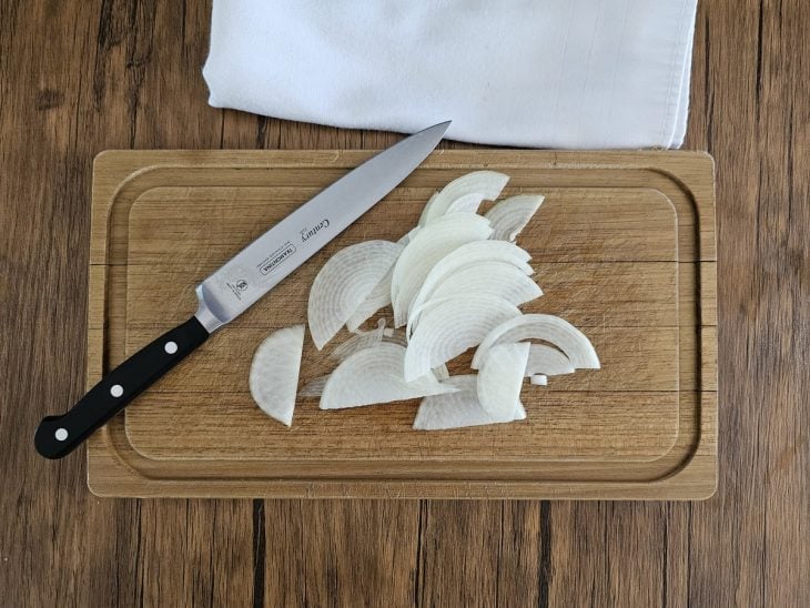 Tábua com cebola cortada em meia-lua.