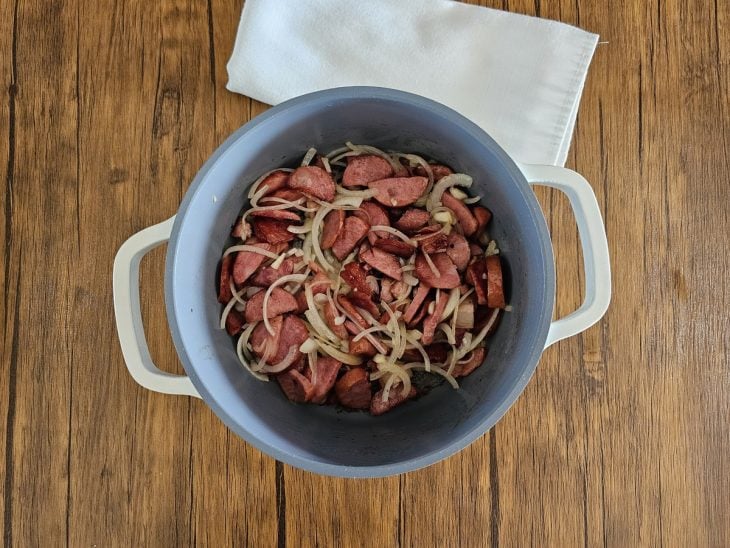 Cebola e alho adicionados à panela com o bacon e a calabresa.