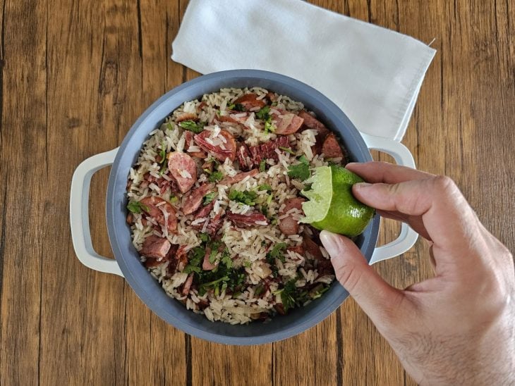 Caldo do limão sendo adicionada à panela com o arroz carreteiro.