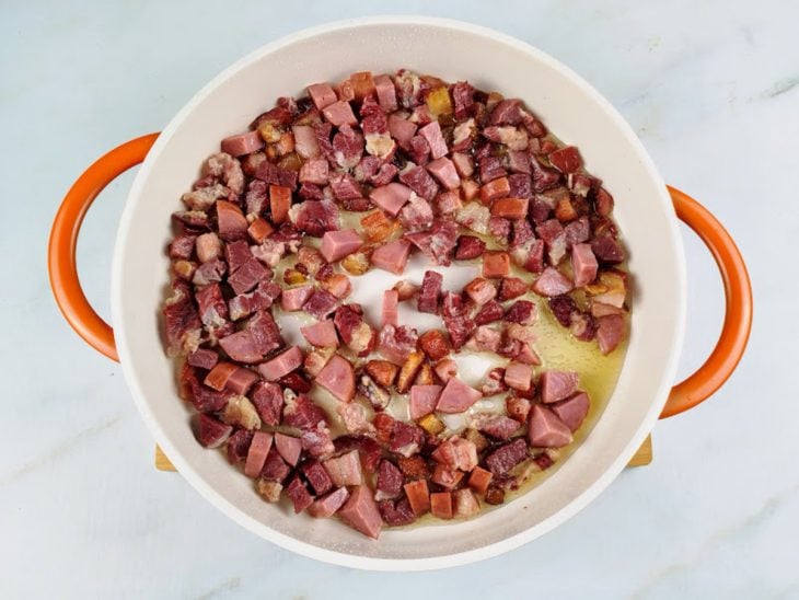 Uma panela com carne-seca, bacon, calabresa.