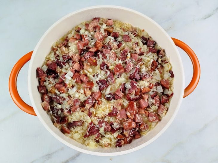 Panela com carnes, arroz, cebola e alho.