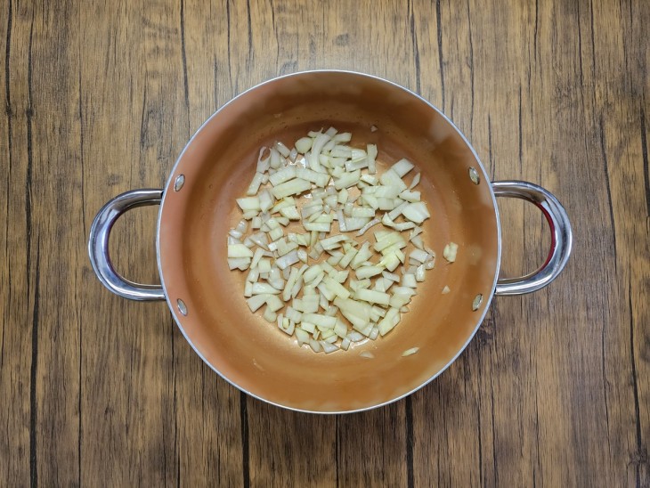 Cebola sendo frita no azeite em uma panela.