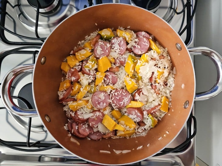 Uma panela contendo abóbora, calabresa, bacon, arroz e sal.