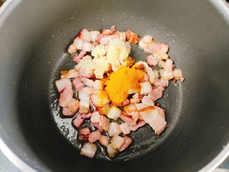 Uma panela com bacon e temperos.