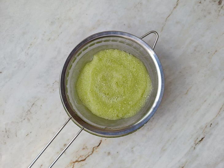Caldo de brócolis sendo coado com peneira fina.