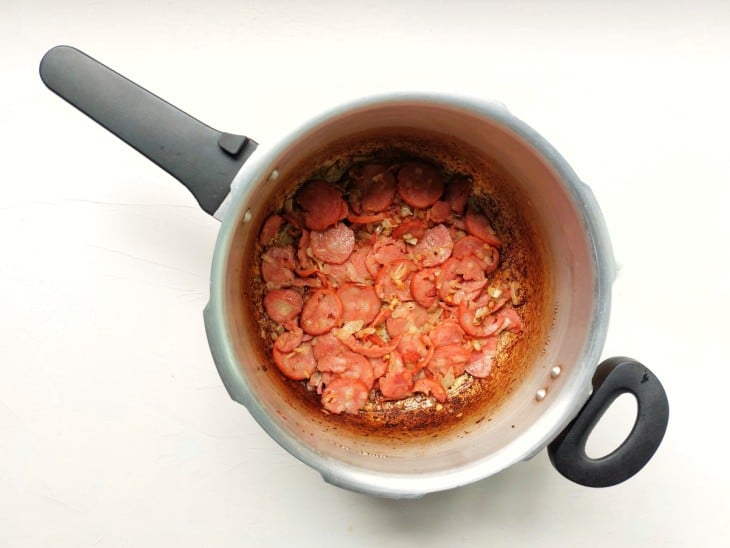 Panela de pressão com linguiça calabresa frita.