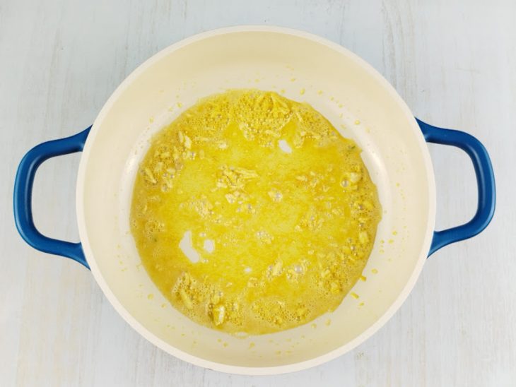 Alho e açafrão sendo refogados em óleo e margarina na panela.