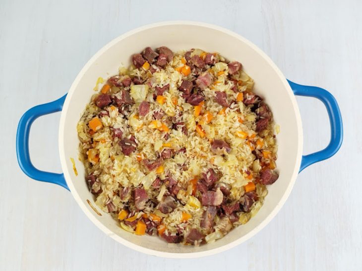 Arroz lavado sendo incorporado ao refogado de charque.