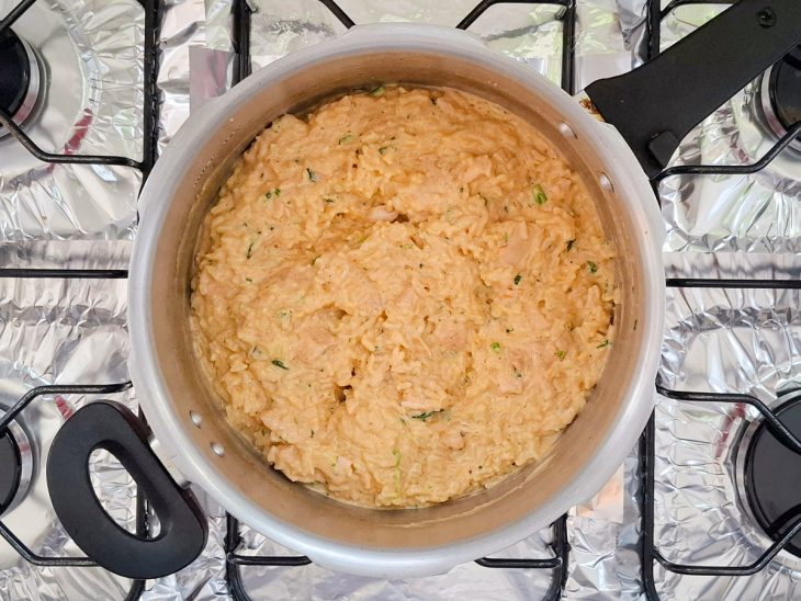 ingredientes adicionados e arroz e frango em ponto cremoso.