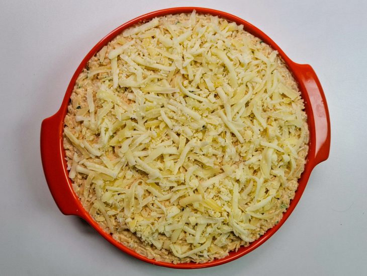 queijo ralado em arroz cremoso em refratário para assar.