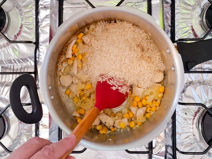 Arroz e tempero baiano adicionado na panela.