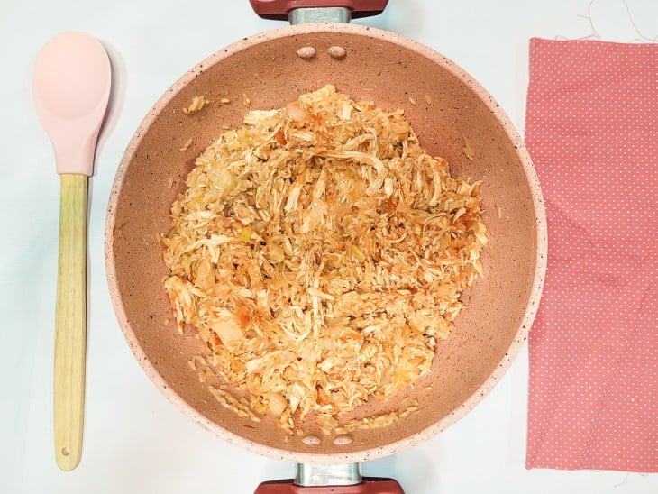 Uma panela com o refogado mais arroz, frango, molho de tomate, sal e pimenta.