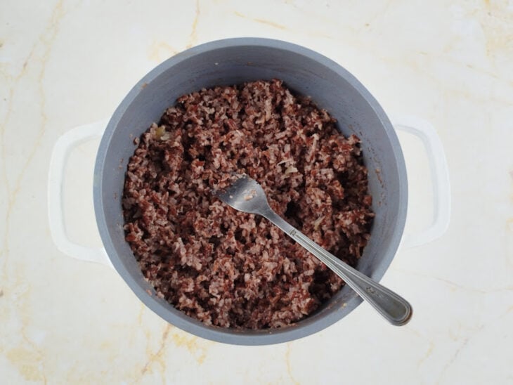 Manteiga de garrafa sendo despejada sobre o arroz finalizado.
