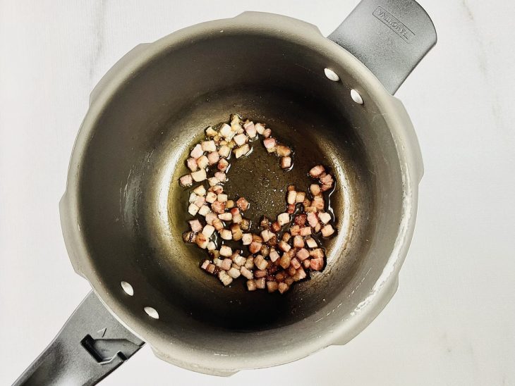 Bacon soltando gordura em uma panela de pressão.