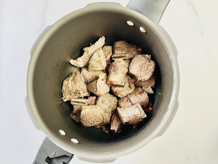Carne temperada com sal e pimenta adicionada a panela.