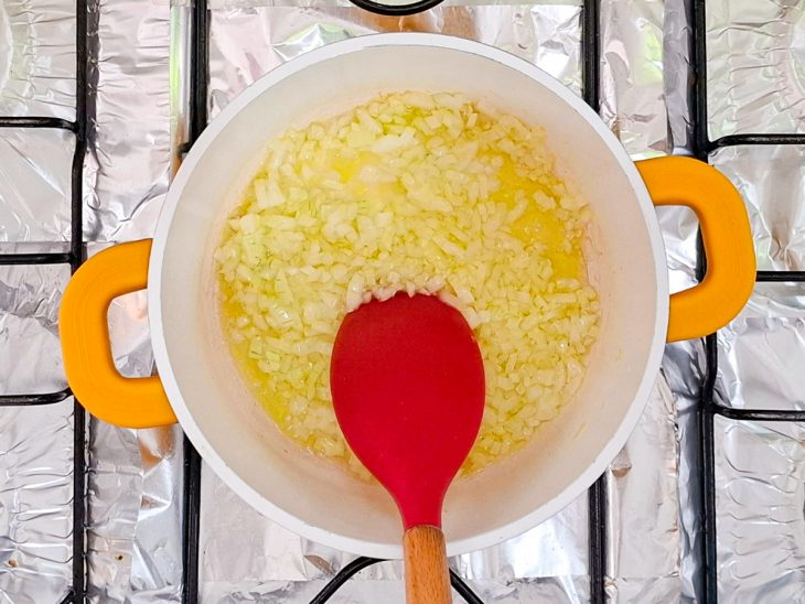 Alho e cebola refogando em uma panela com azeite.