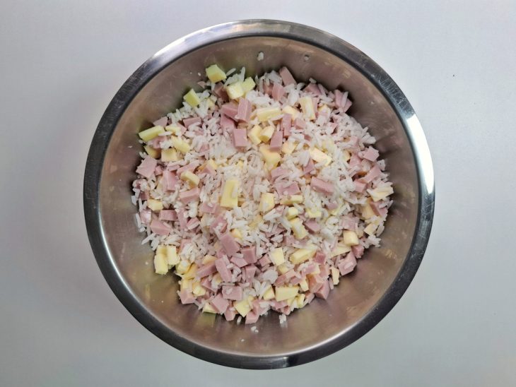 Arroz cozido, presunto e mussarela misturados em uma tigela de alumínio.