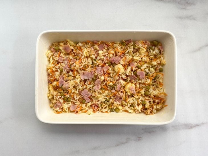 Um refratário forrada com creme e com uma camada do arroz temperado.