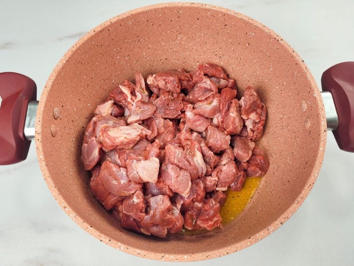 Uma panela refogando cubis de carne.