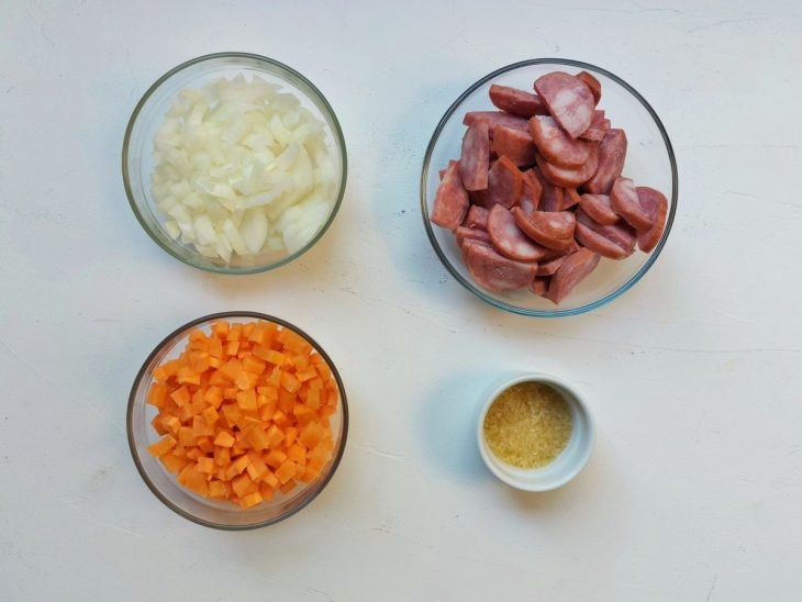 Recipiente contendo legumes e calabresas cortadas.