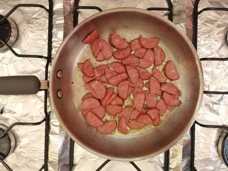 Uma panela fritando calabresa.
