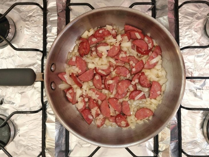 Uma panela refogando calabresa e cebolas.