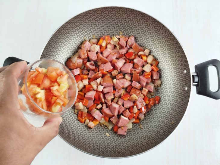 Na panela, os tomates sendo adicionados.
